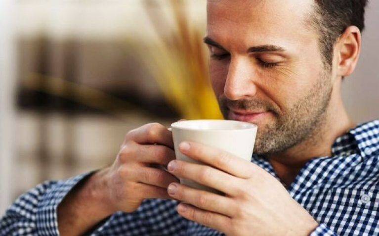 En man dricker en drink te för att öka styrkan